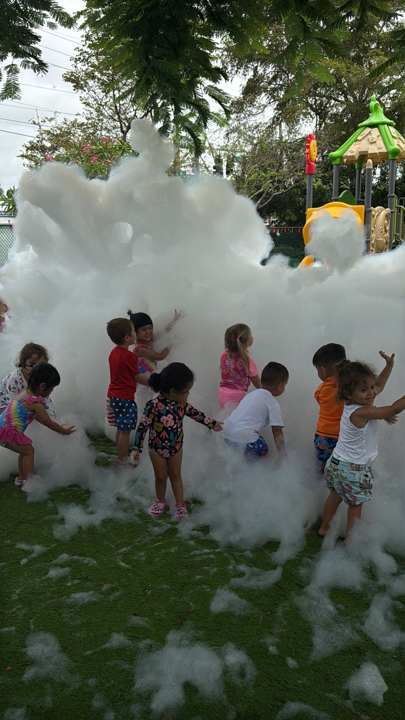 Kids playing in foam by a playground wall at a Zombie Truck Foam Experience party